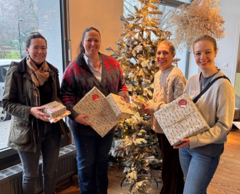ein-packerl-team-mit-geschenken-am-christbaum